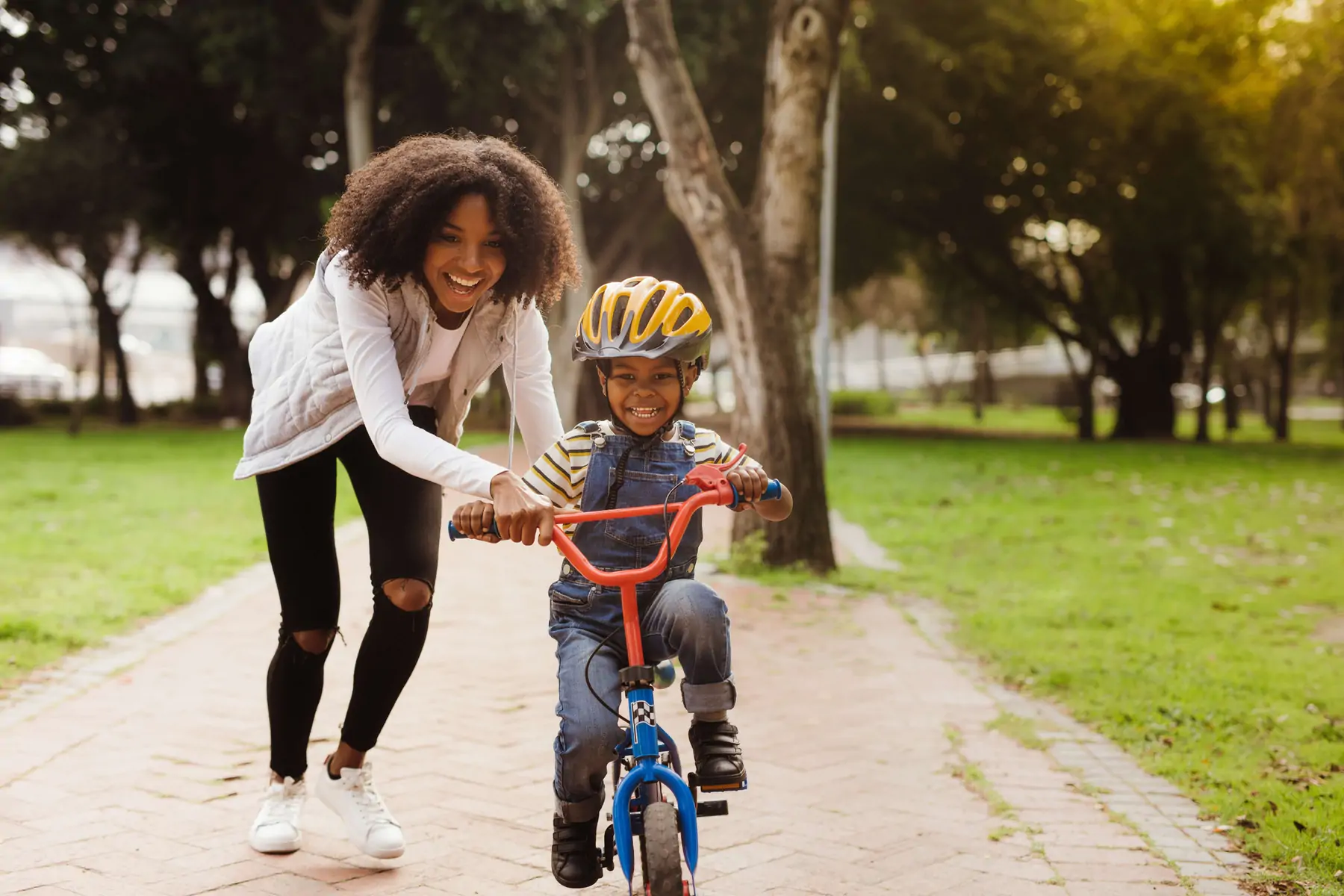 Black single mom, helping son ride bike.